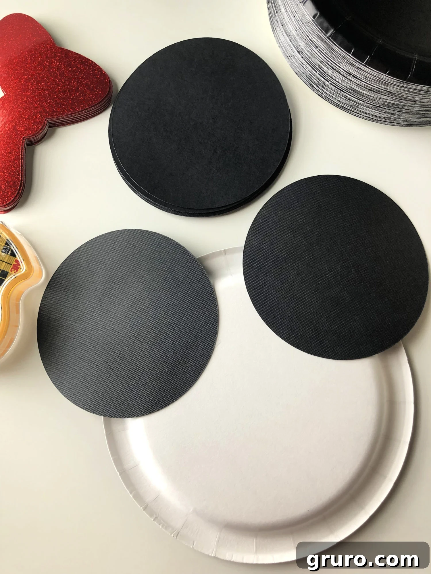 DIY Minnie Mouse Paper Plates Step 2 - Attaching black cardstock circles as Minnie's ears to the paper plate.