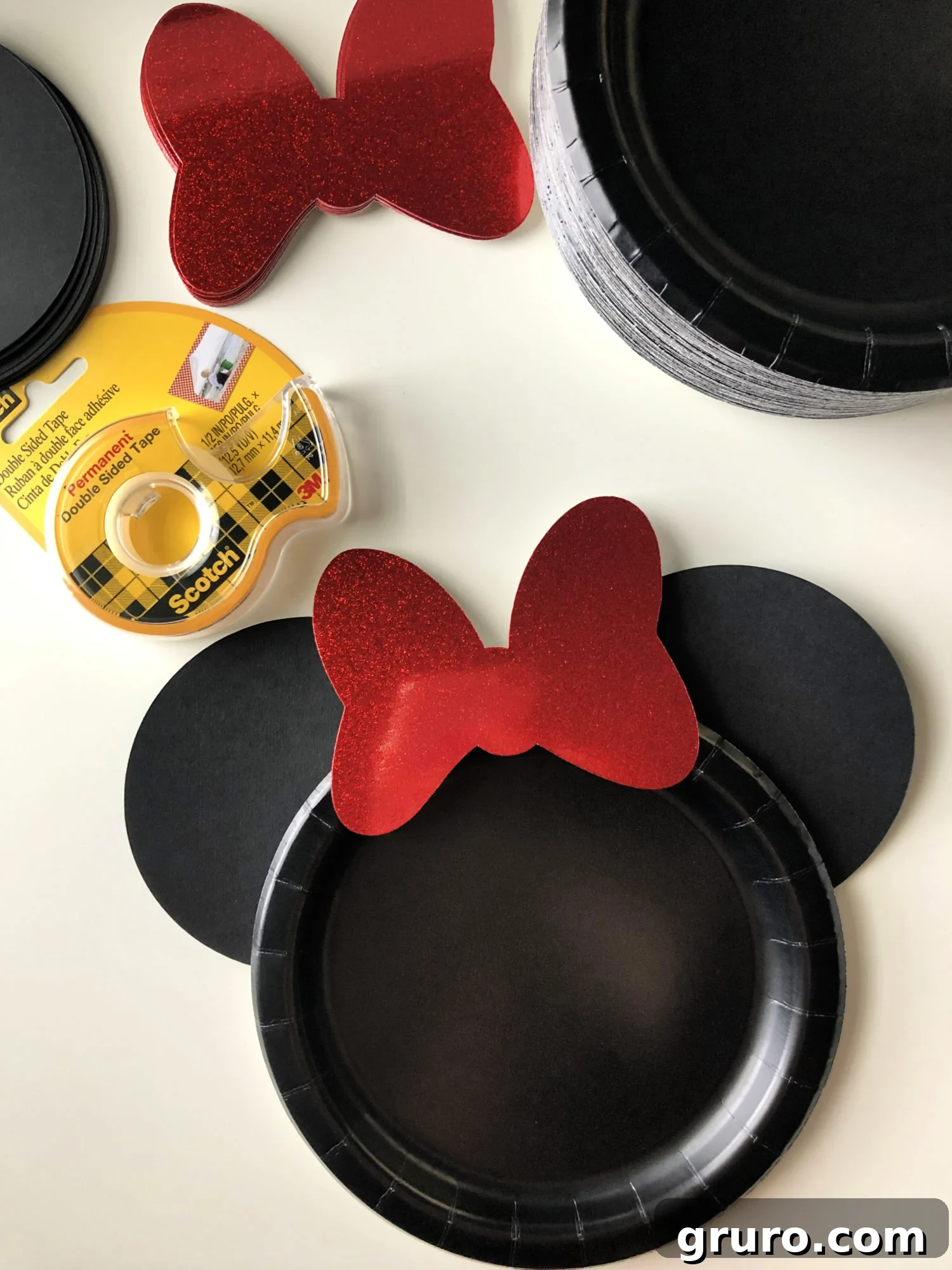 DIY Minnie Mouse Paper Plates Step 4 - Attaching the red shimmer bow to complete the Minnie Mouse plate.