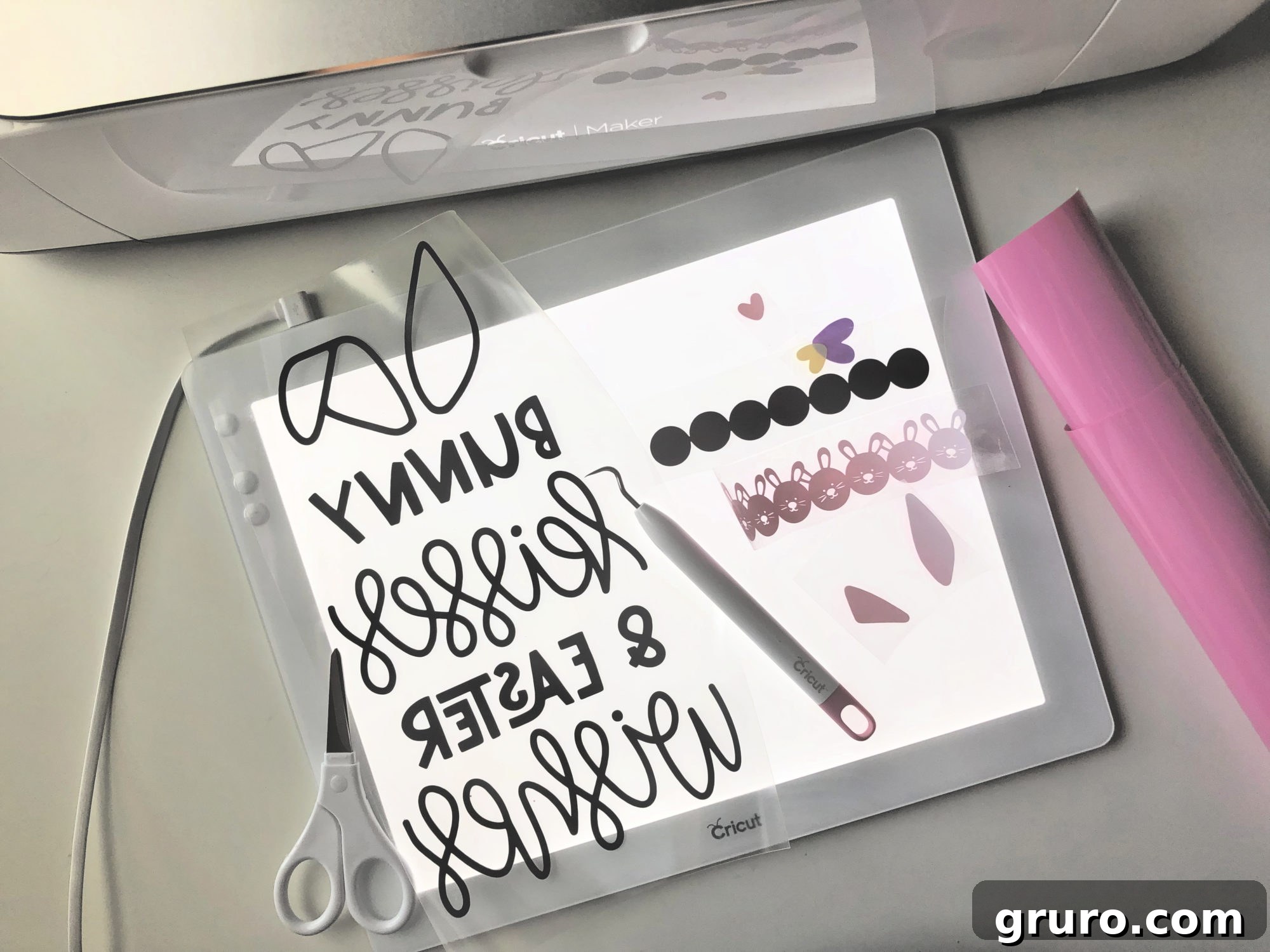 Weeding Iron-On Vinyl for the Bunny Kisses & Easter Wishes Burlap Garden Flag using a Cricut BrightPad and weeding tools.