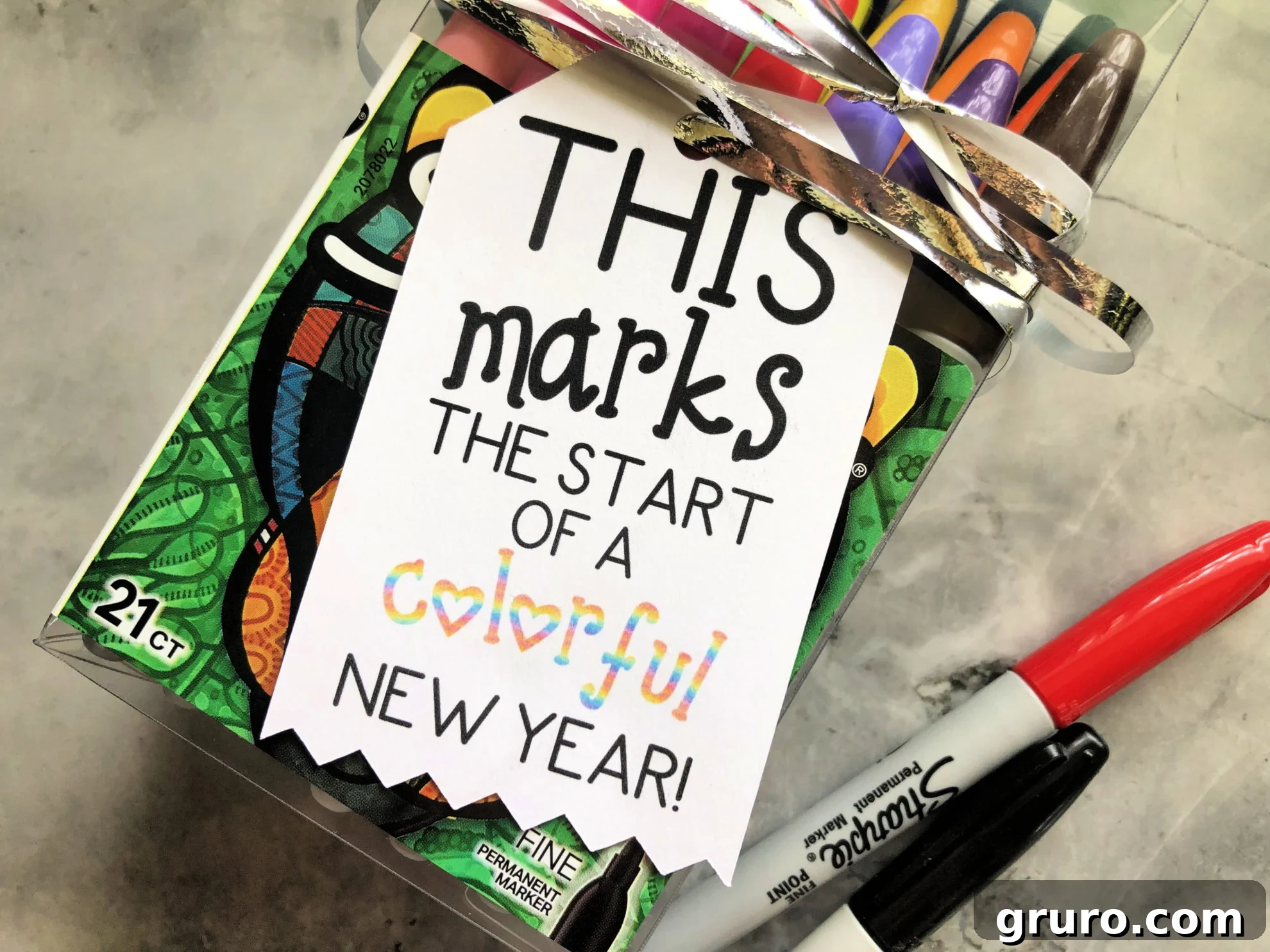 Close up of a tag that reads "this marks the start..." on a marble countertop with sharpies.