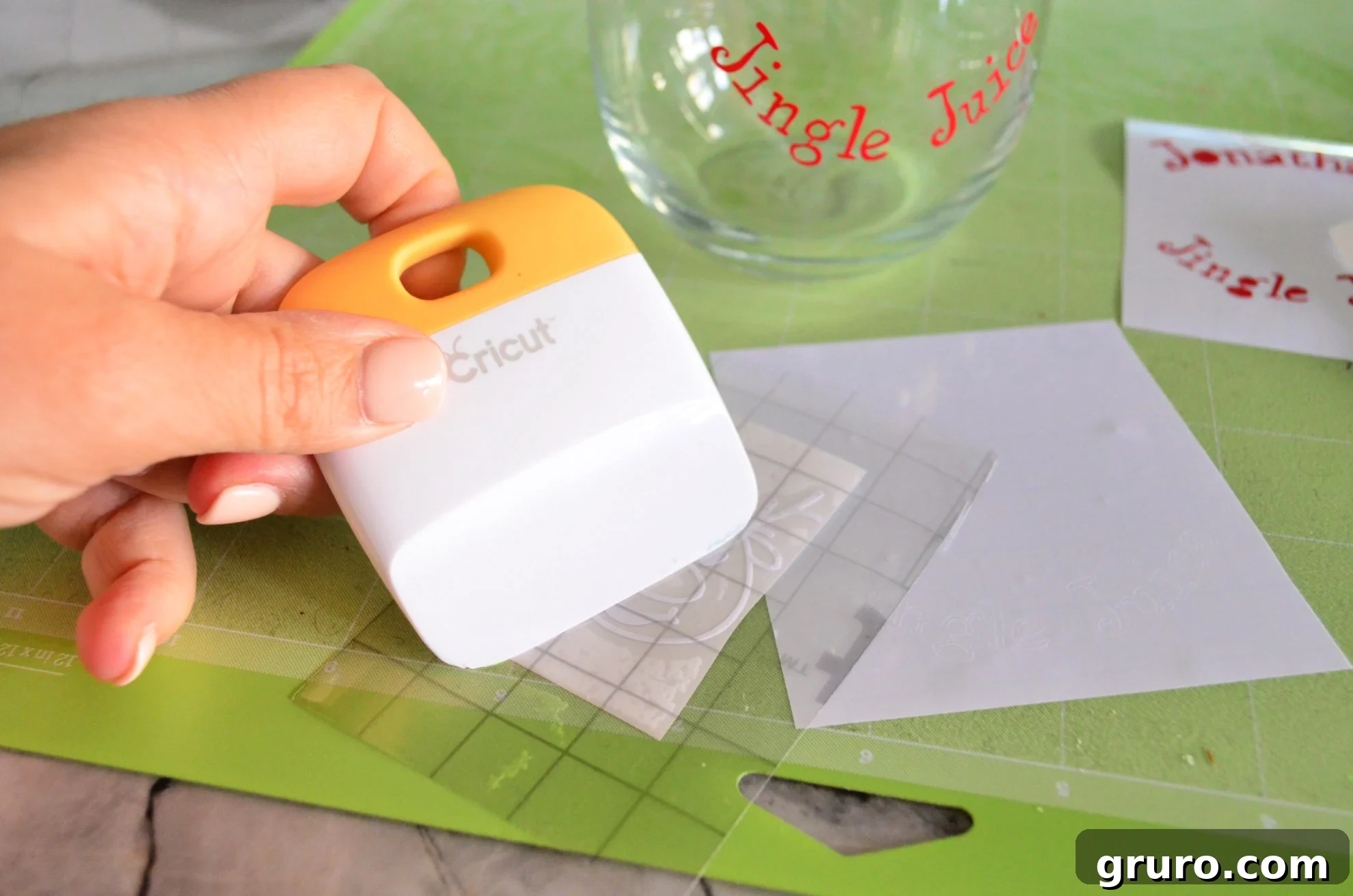 Squeegeeing reindeer emoji vinyl onto transfer tape
