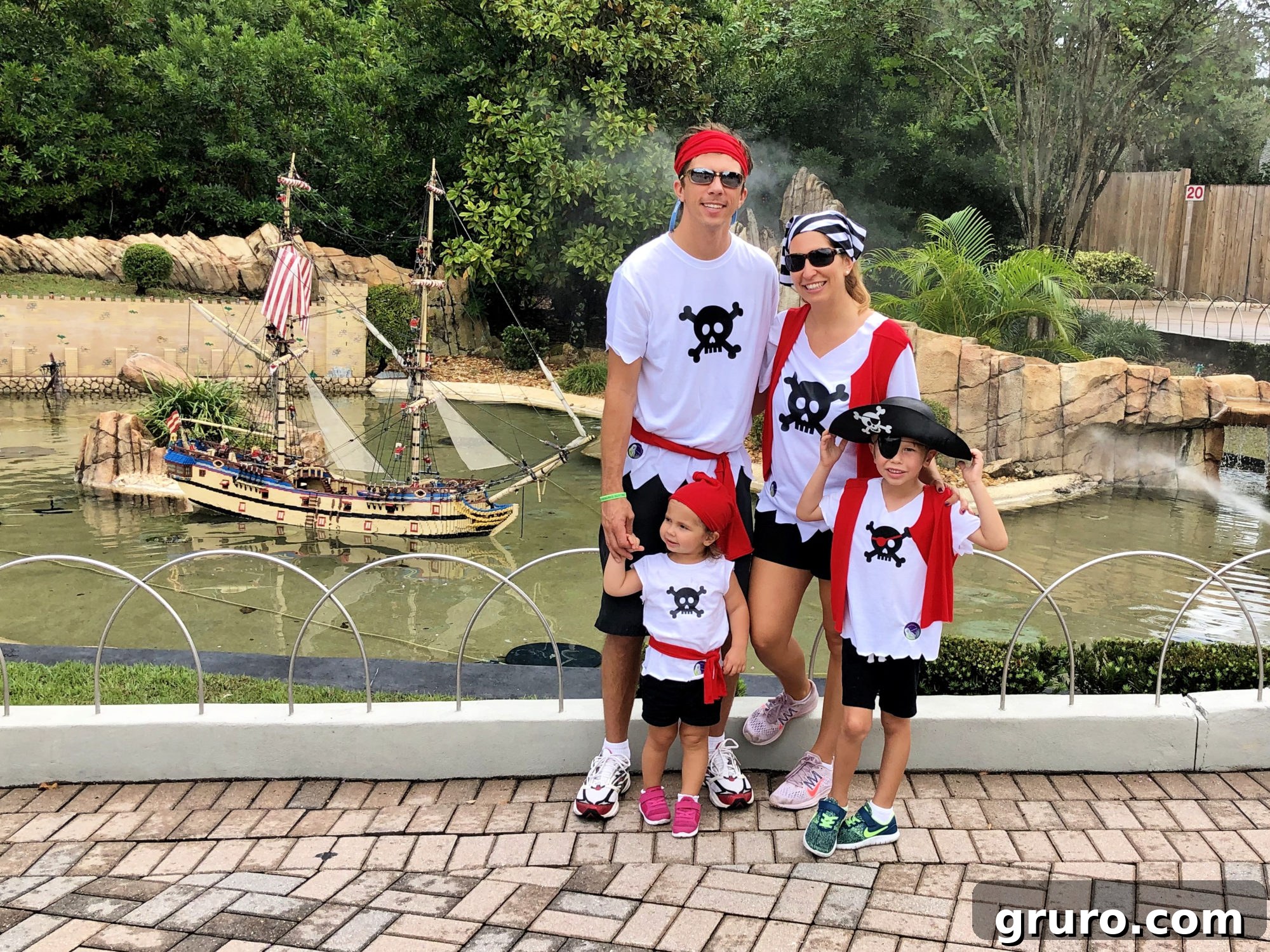 A family dressed in DIY Pirate Costumes, featuring customized white shirts with pirate skull designs, red vests, and bandanas.