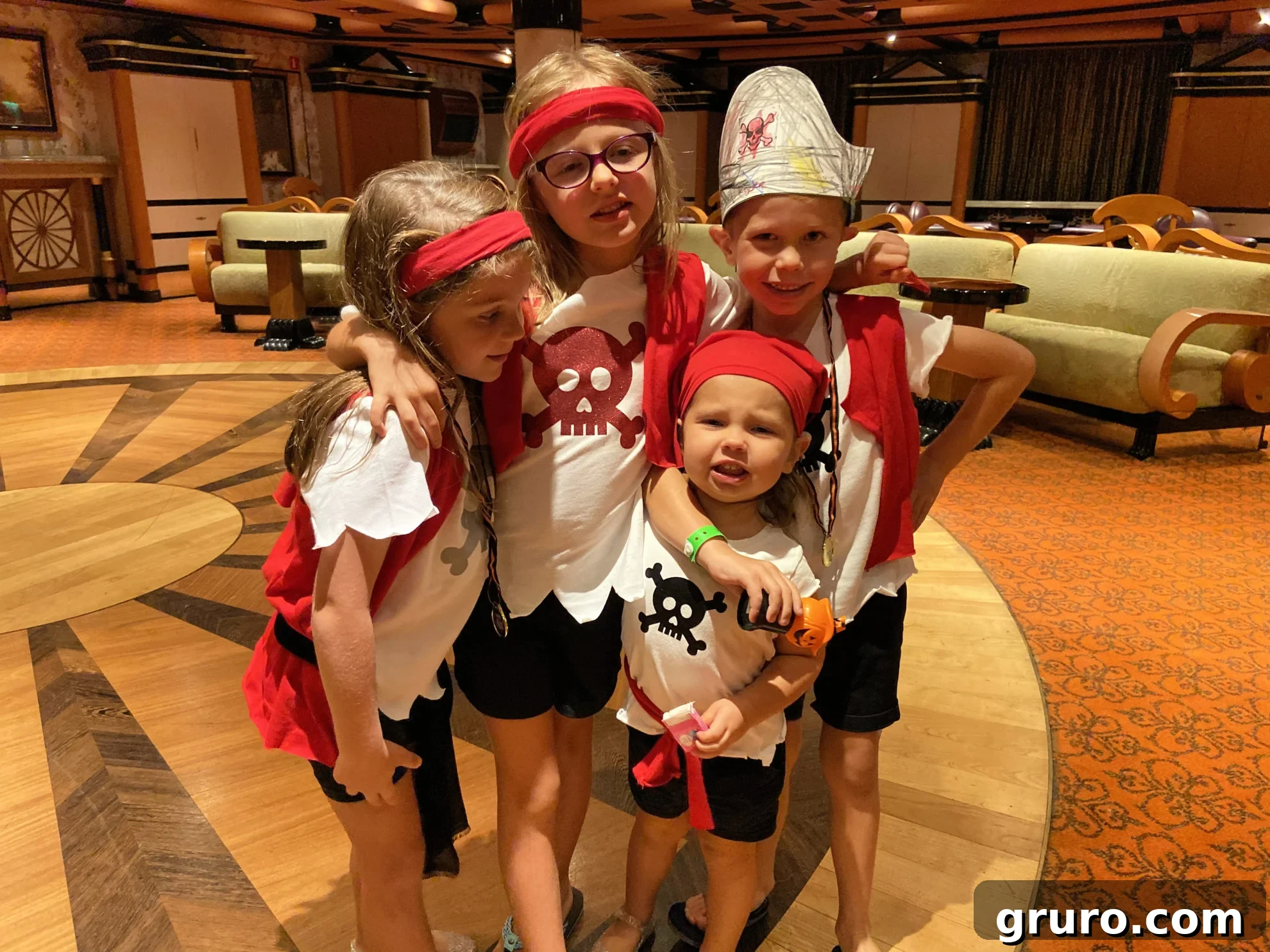 Four children happily posing in their homemade pirate shirts, demonstrating the variety and fun of customized family costumes.