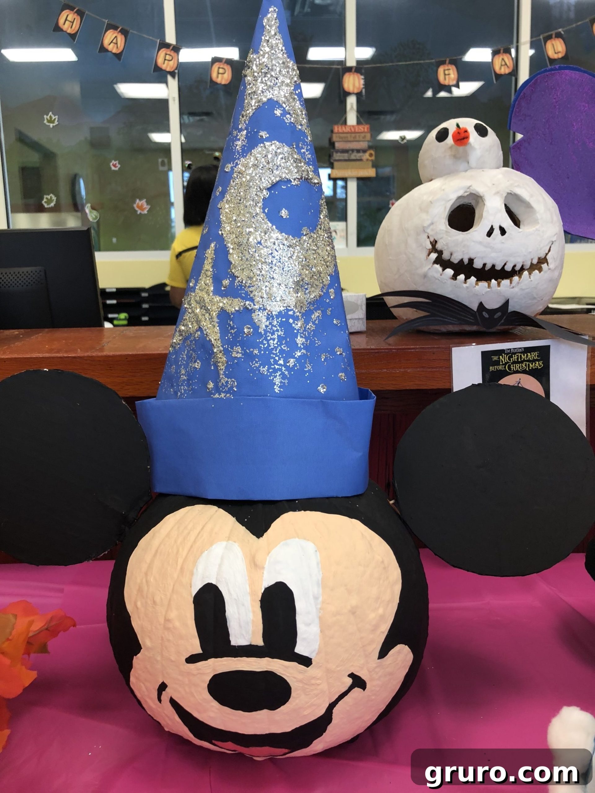 15 Creative No-Carve Pumpkin Decorations 13 A Sorcerer Mickey Mouse painted pumpkin featuring cardboard ears and a blue wizard hat, sparkling with glitter.
