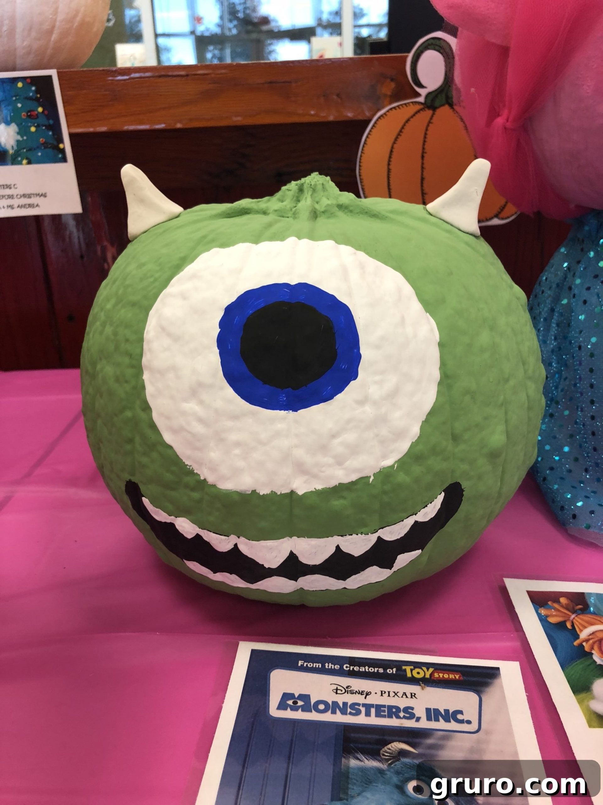 15 Creative No-Carve Pumpkin Decorations 7 A bright green Mike Wazowski No-Carve Pumpkin featuring his iconic single eye, displayed on a pink table.