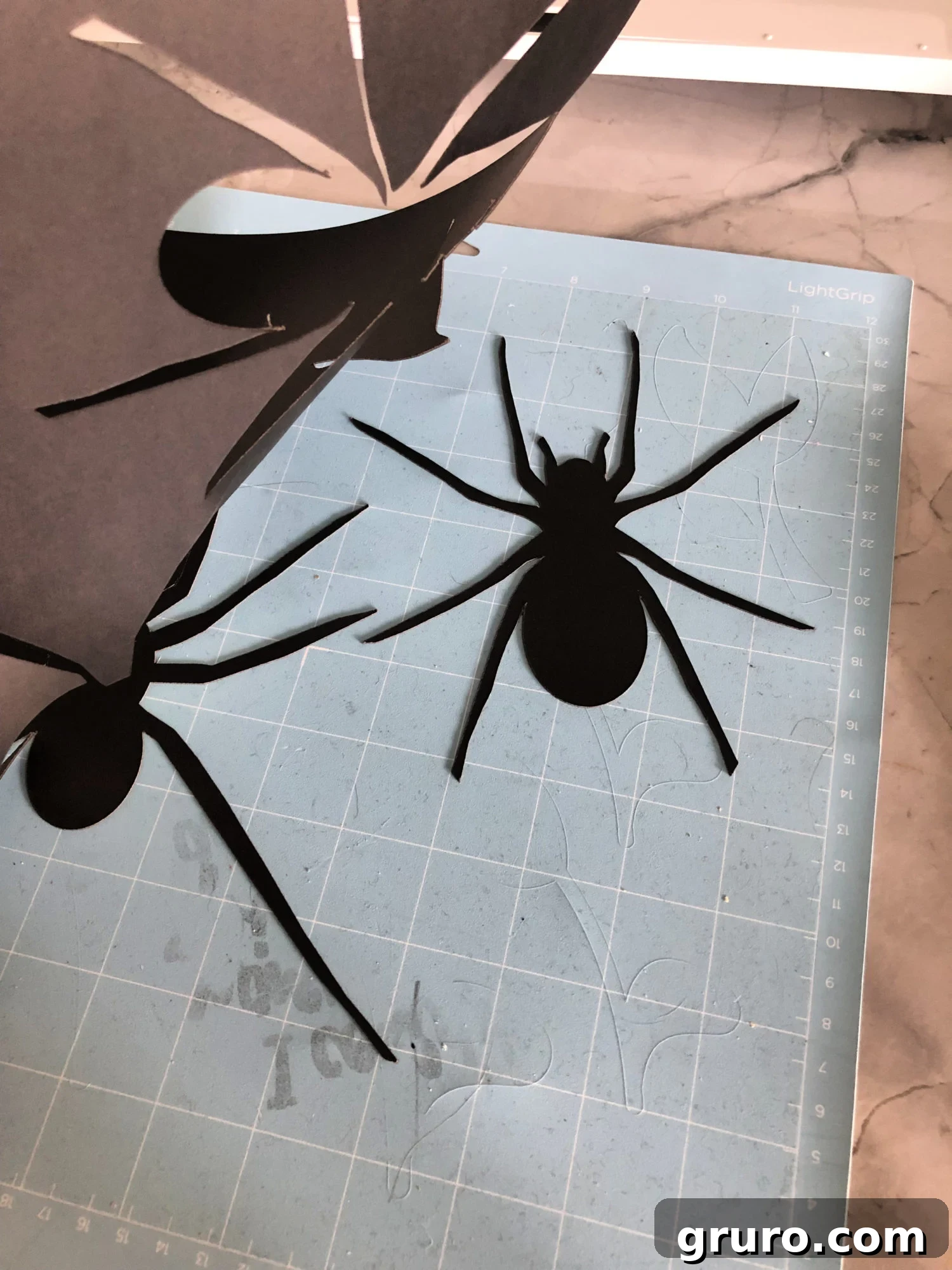Cut paper spiders on a Cricut mat, ready for removal.