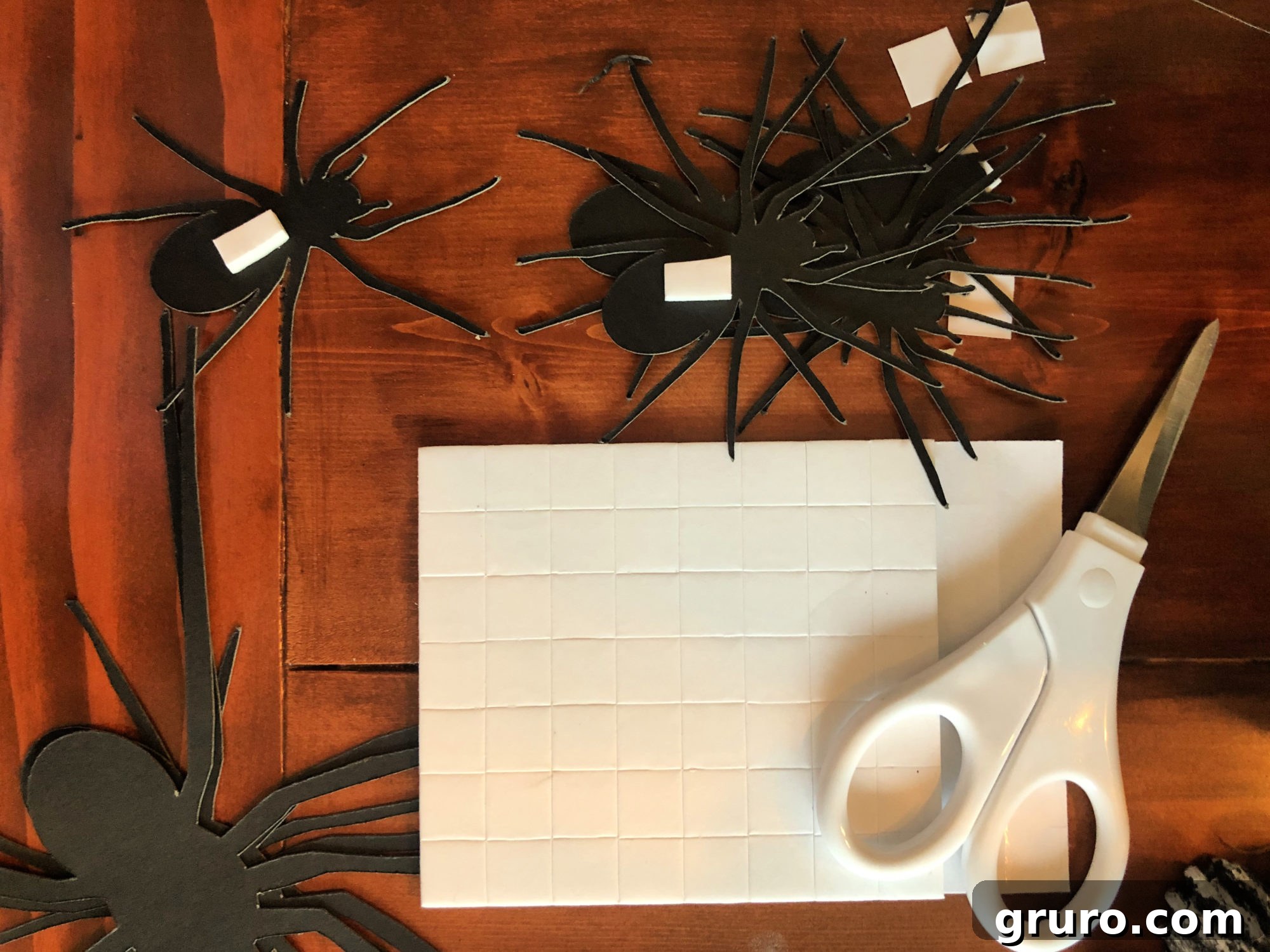 Applying 3D dot stickers to the back of a paper spider.