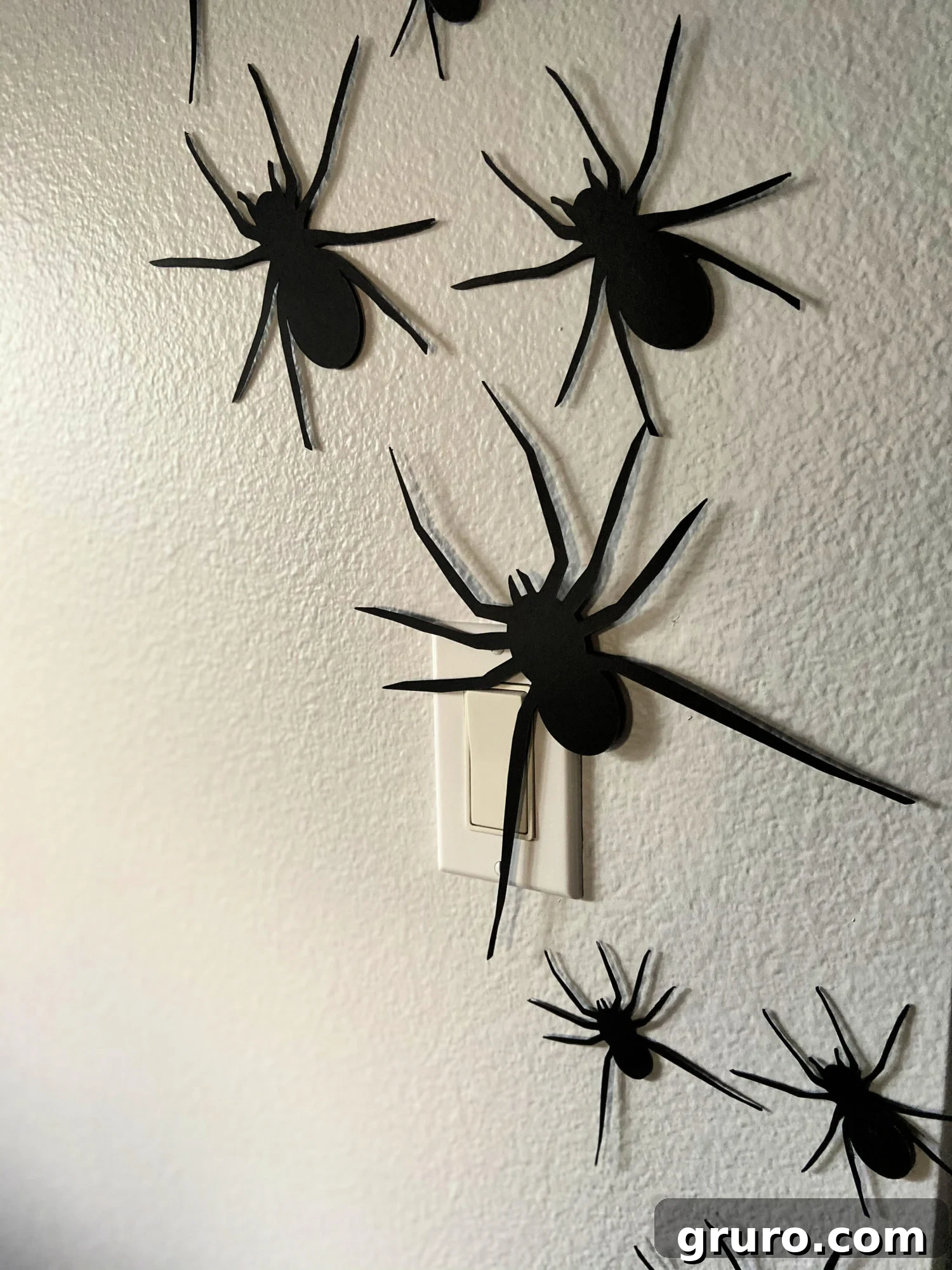 Close-up of DIY paper spiders on a wall, showing dimension and placement.