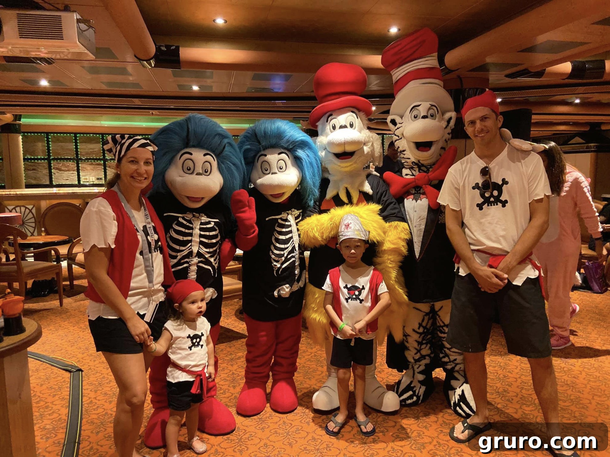 A family dressed as pirates posing cheerfully with Dr. Seuss characters: Thing 1 and Thing 2, Sam I Am, and the Cat in the Hat.