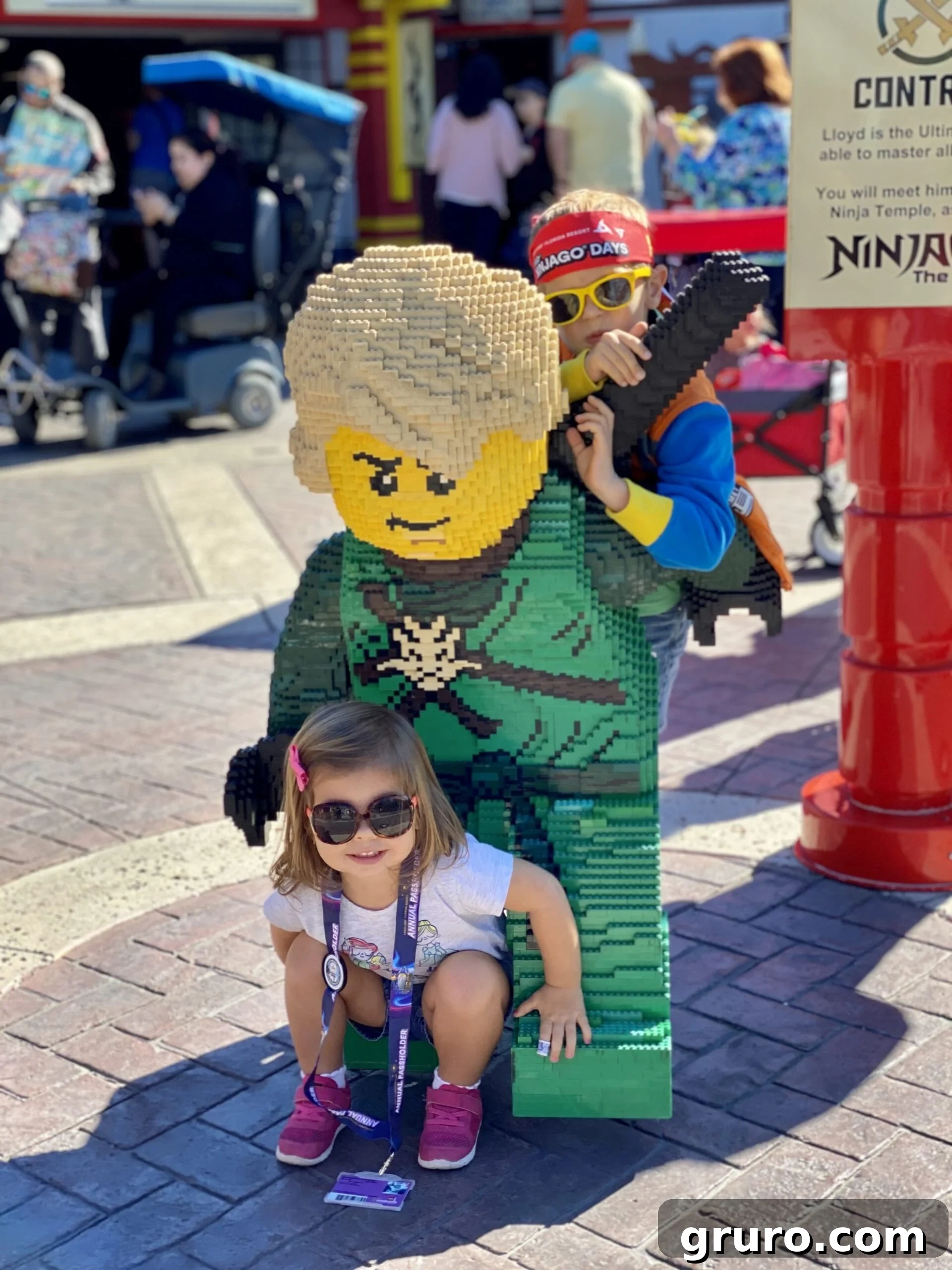 Little girl sitting on Ninjago life size brick figure.