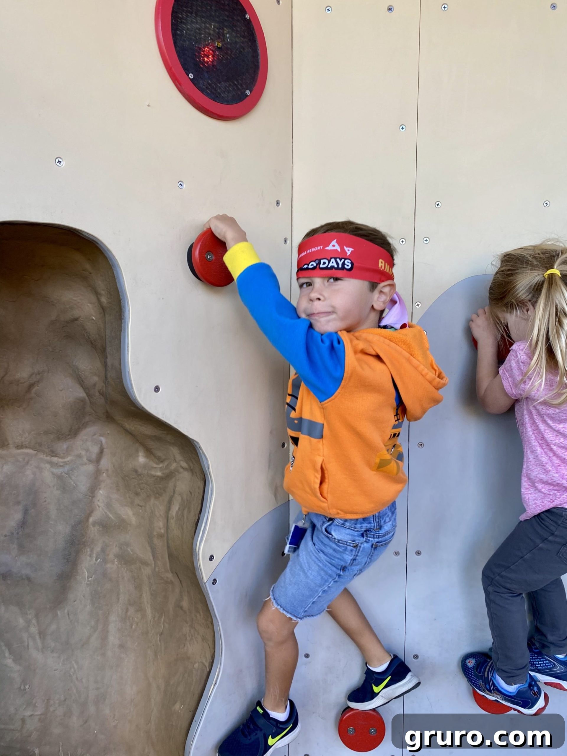Little boy with red headband climbing in Ninjago land