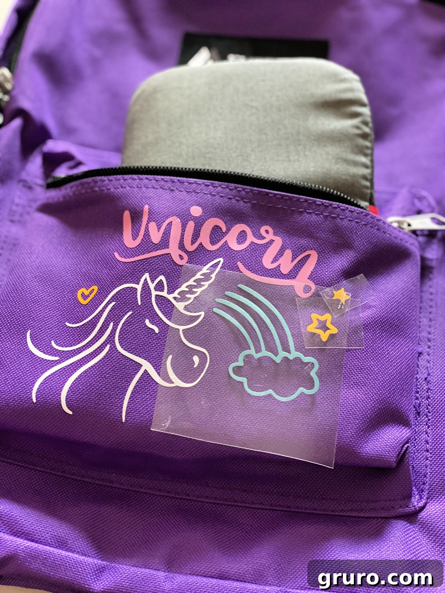 Adding the second layer of unicorn iron-on vinyl to the backpack