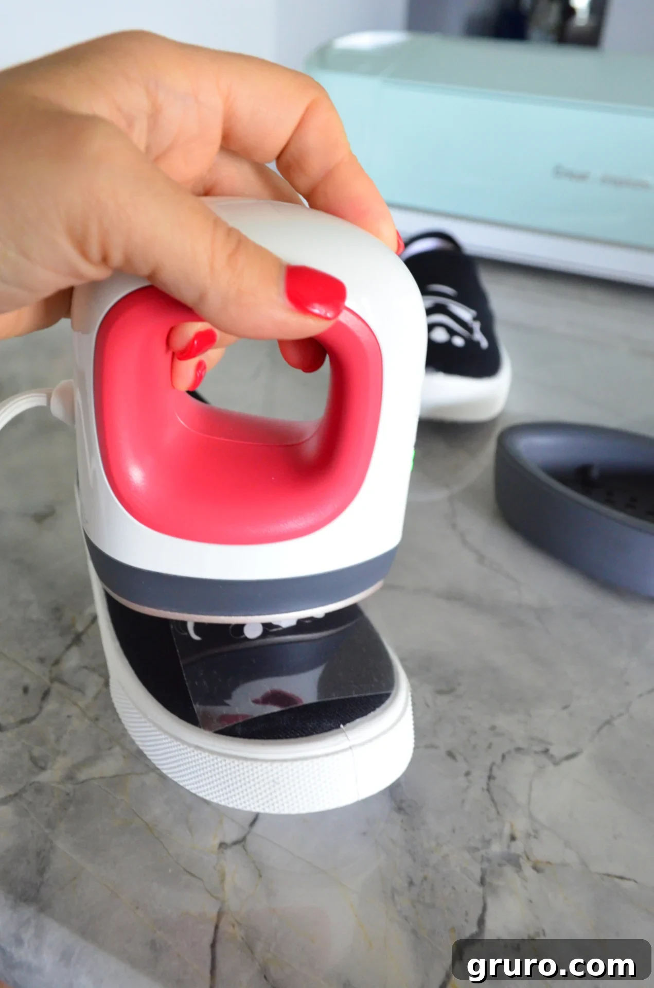 A Cricut EasyPress Mini applying heat to a Stormtrooper helmet iron-on vinyl design on a canvas shoe, with the design being pressed firmly.