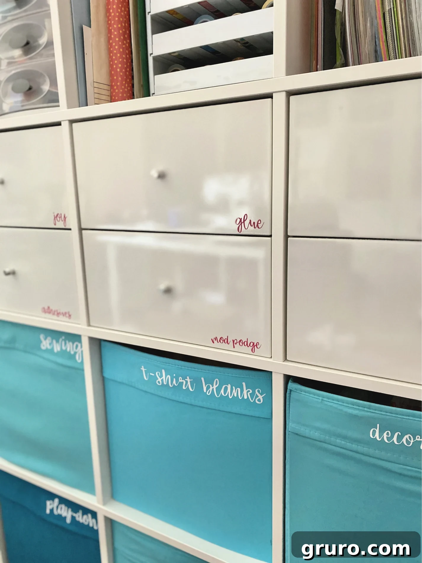 White craft drawers, each neatly adorned with tiny pink vinyl labels, showcasing a beautifully organized and visually appealing craft storage system. The labels make it easy to identify contents at a glance.