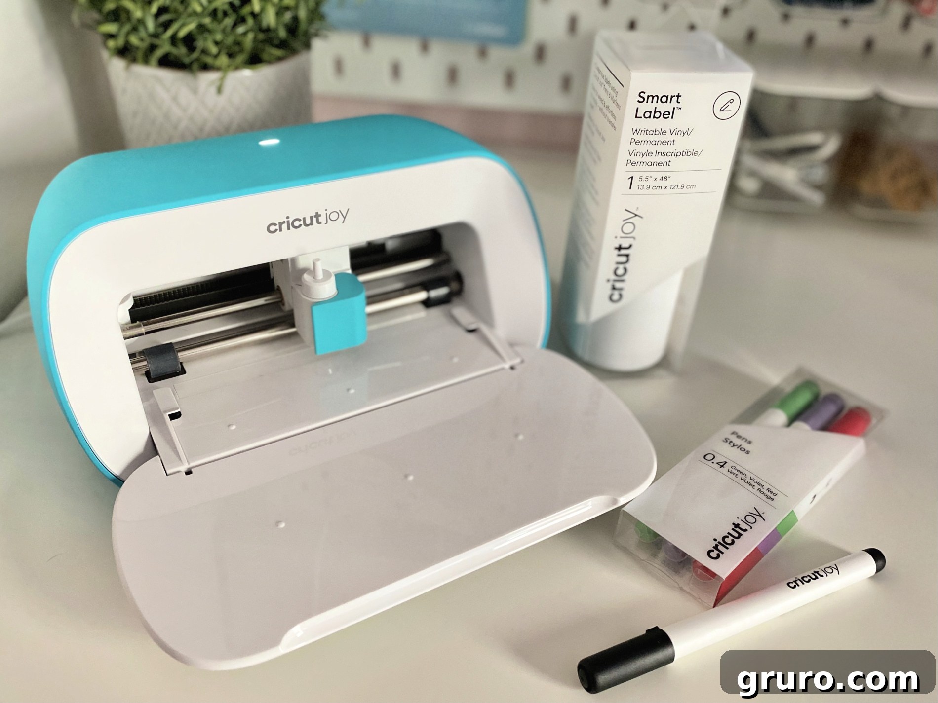 Cricut Joy machine positioned alongside Cricut Joy Smart Label Writable Vinyl and a set of Cricut Joy Fine Point Pens, illustrating the essential supplies for creating custom writable labels for jars.