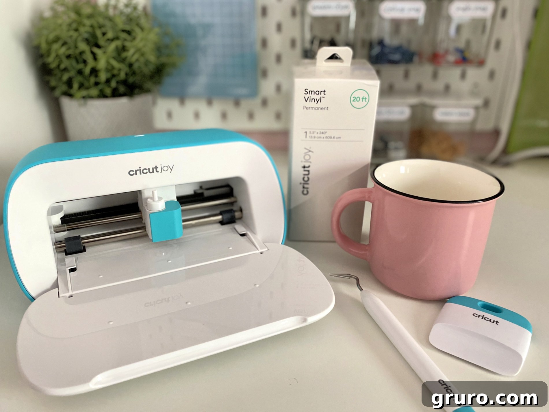 Cricut Joy machine displayed with Cricut Joy Smart Vinyl, a roll of Transfer Tape, and various Cricut Joy Tools, indicating all necessary items for crafting a personalized vinyl decal for a mug.