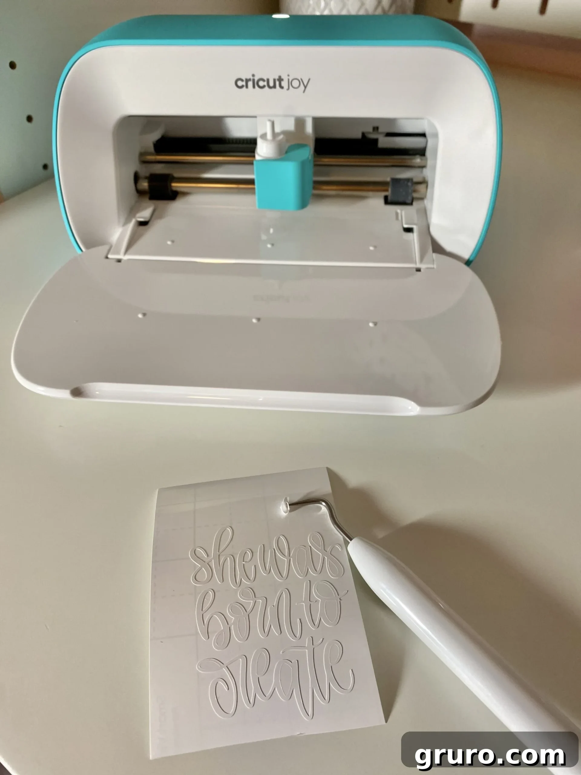 Close-up of a hand using a weeding tool to remove excess Smart Vinyl from around a cut design, leaving the intricate pattern on its liner.