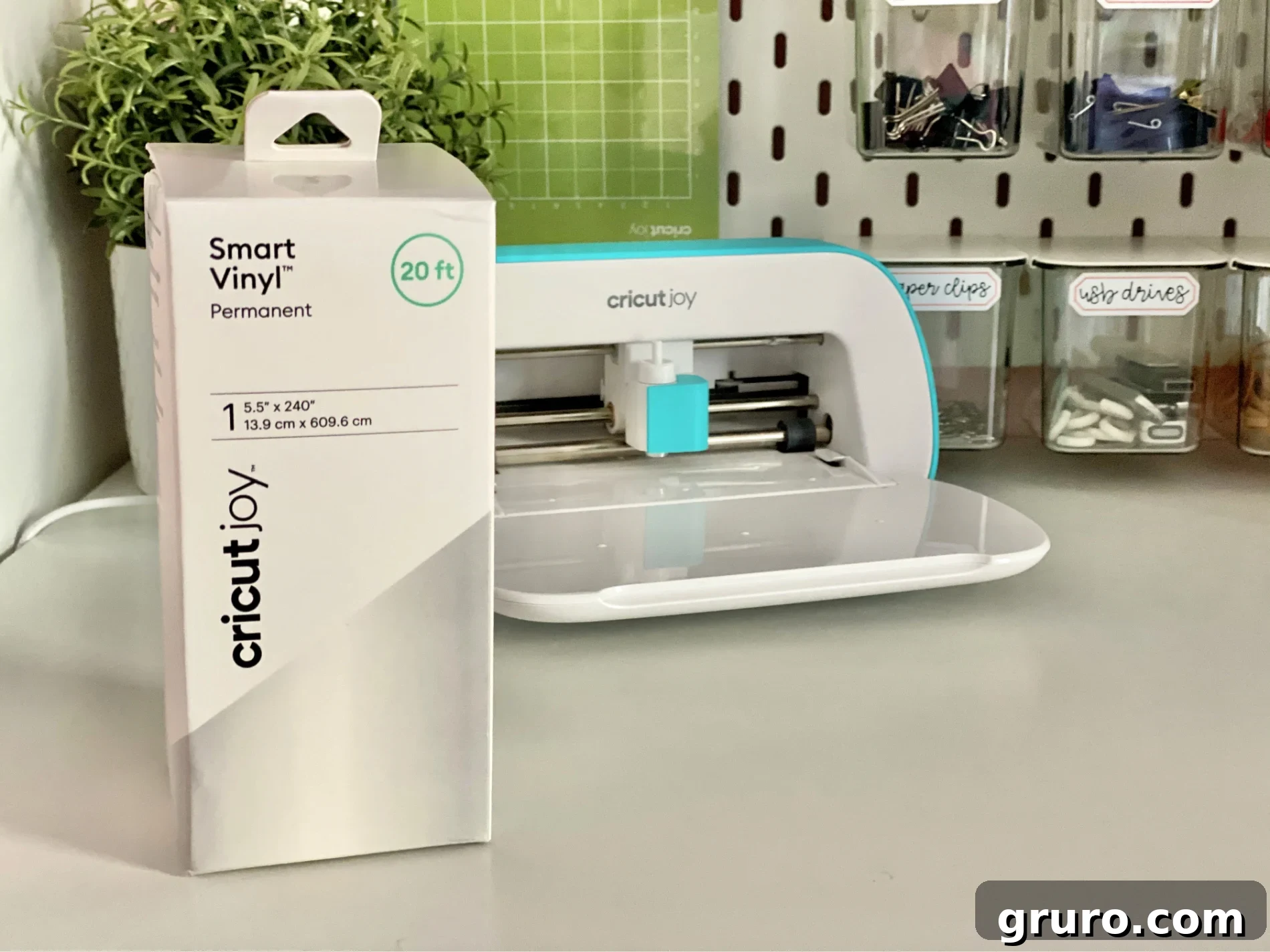 An open box of Smart Vinyl stands on a clean white table, with a sleek Cricut Joy machine visible in the soft-focus background, ready for action.