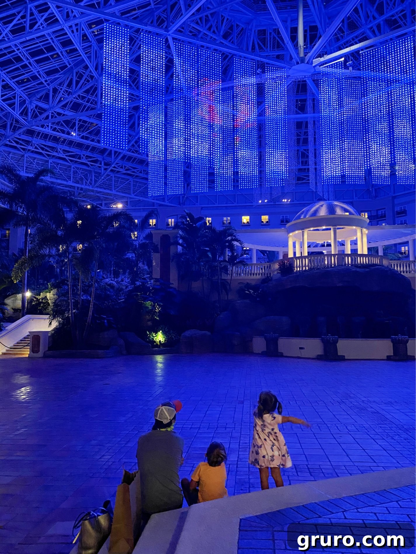 Father and children sitting on steps watching light show in a hotel. 