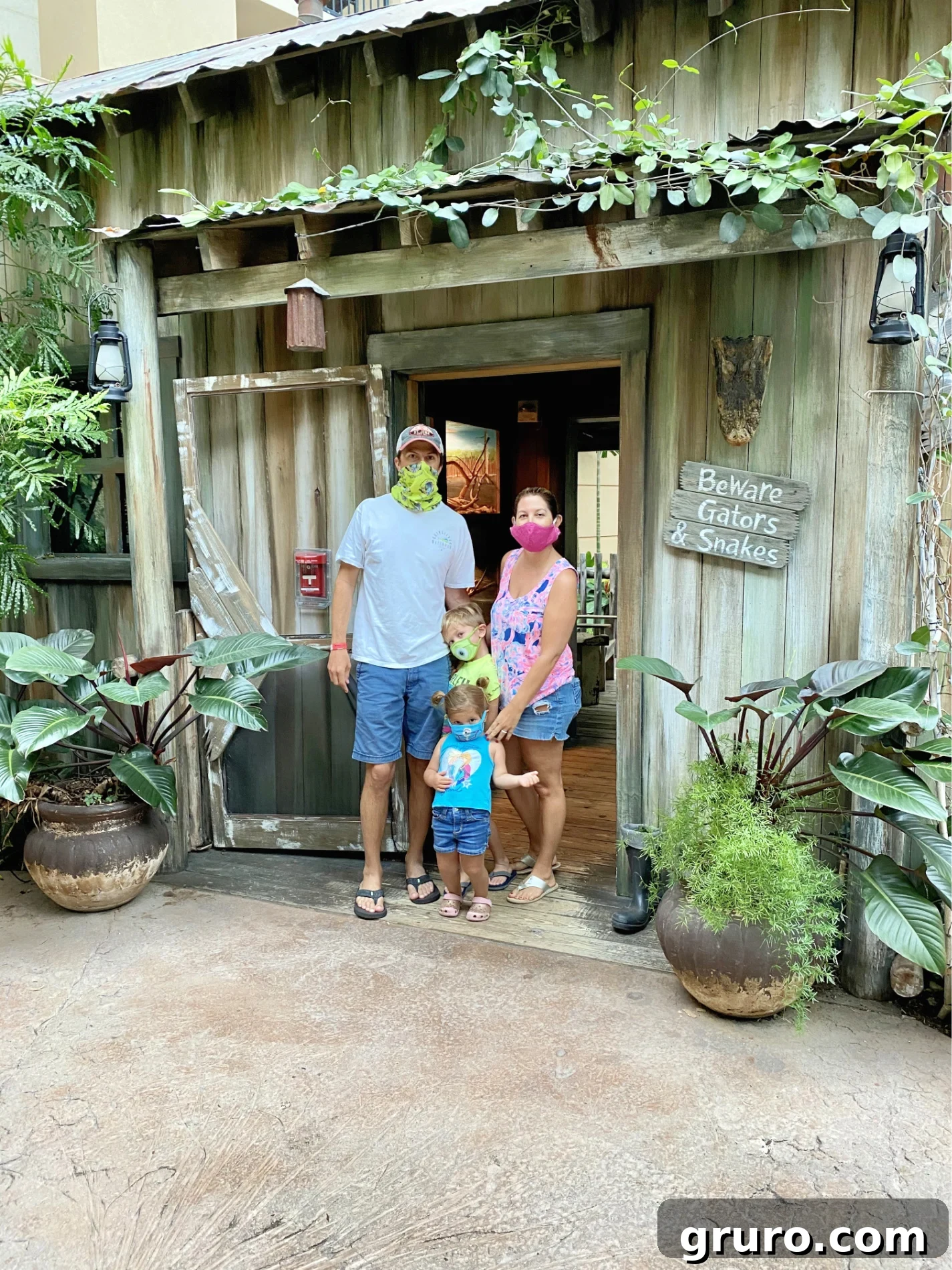 Family with mask on standing in front of house with plants.
