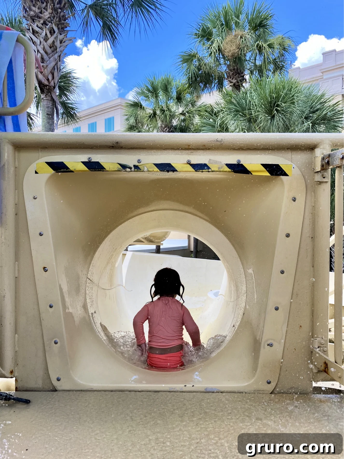Little girl sliding down on her bottom on a water slide. 