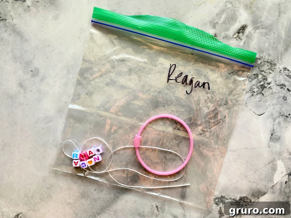 Bag with the name "reagan" with a pink round bracelette with necklace thread and lettered beads.