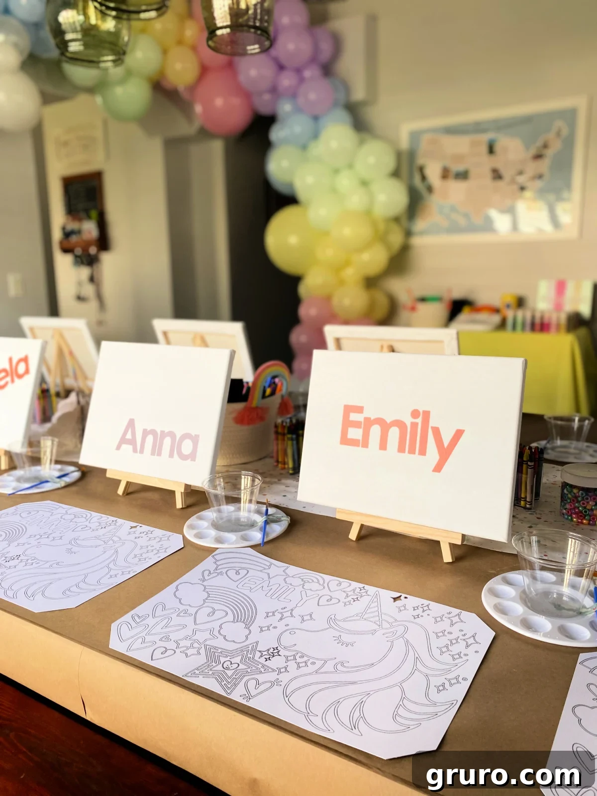 Two canvasses with coloring placemat and rainbow balloon arch in the background.