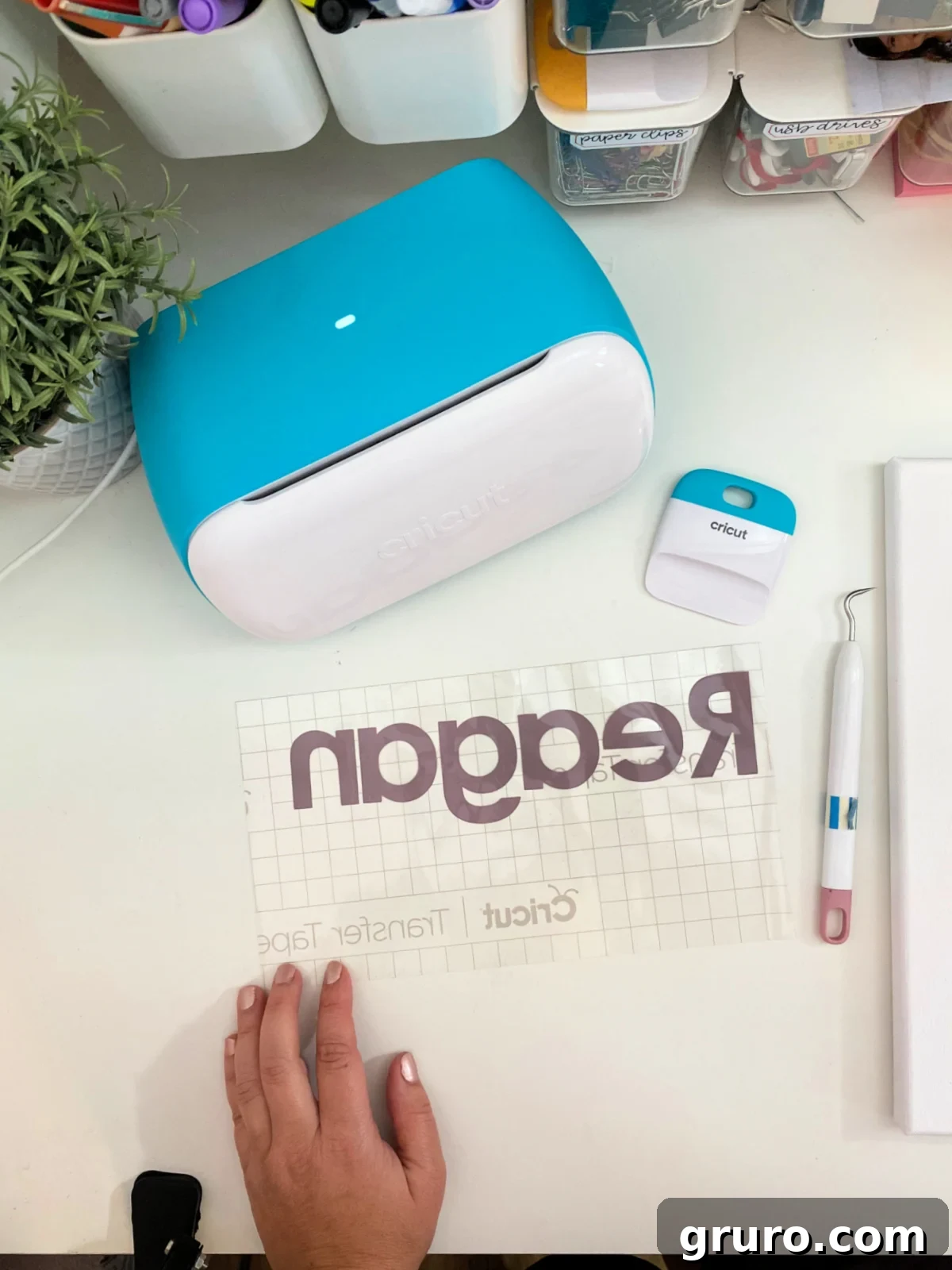 Cricut Joy on a white desk with vinyl on transfer tape and a cricut squeege.
