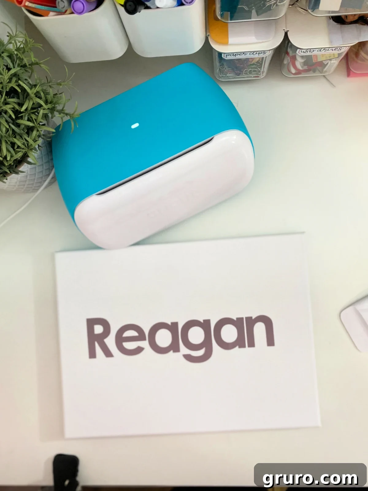 Cricut Joy on a white table with a canvas with vinyl that says "Reagan".