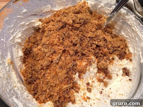 Mixing crushed Butterfinger into creamy pie filling