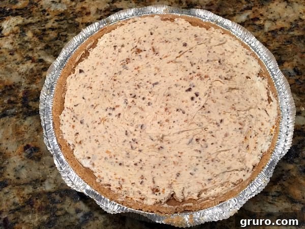Pouring Butterfinger pie mixture into graham cracker crust