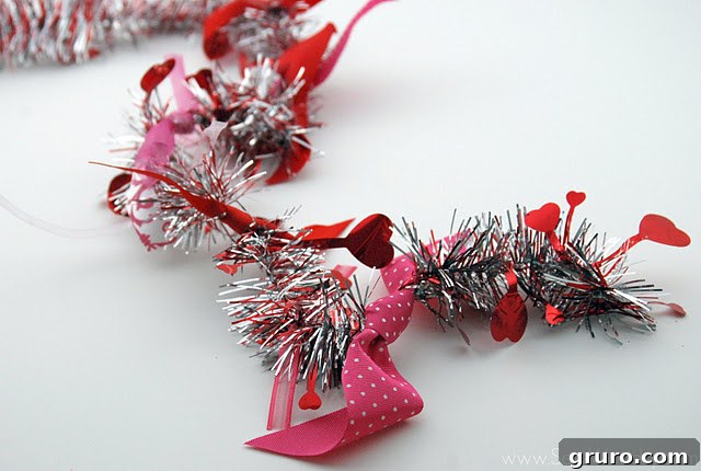 A plain tinsel garland gradually being adorned with tied scraps of colorful ribbon, demonstrating the tying process.