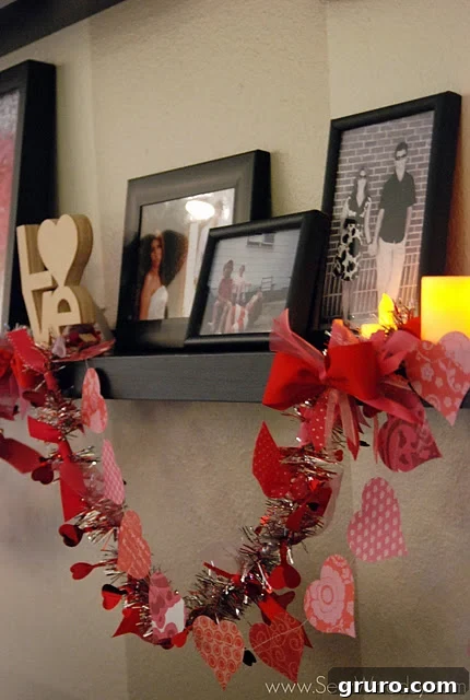 A beautifully decorated black shelf adorned with the finished Valentine's garland, from which several paper hearts are elegantly hanging.
