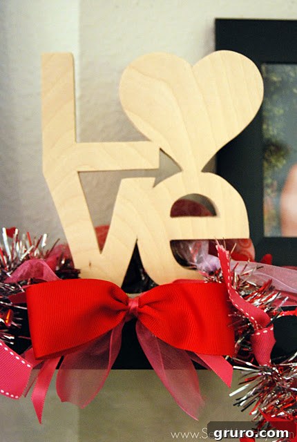 A rustic wooden 'LOVE' sign beautifully adorned with the handmade ribbon garland, creating a charming focal point.