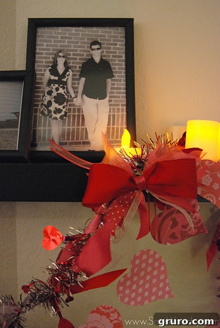 A close-up of a vibrant ribbon and bow garland draped gracefully on a black shelf, accompanied by a picture frame showcasing a happy couple, creating a warm and personal display.