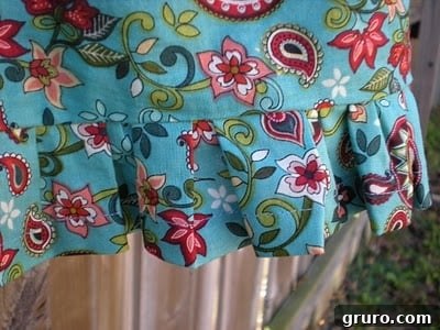 Close-up of a sewing machine stitching fabric, likely connecting the skirt to the tank top for the toddler dress project.