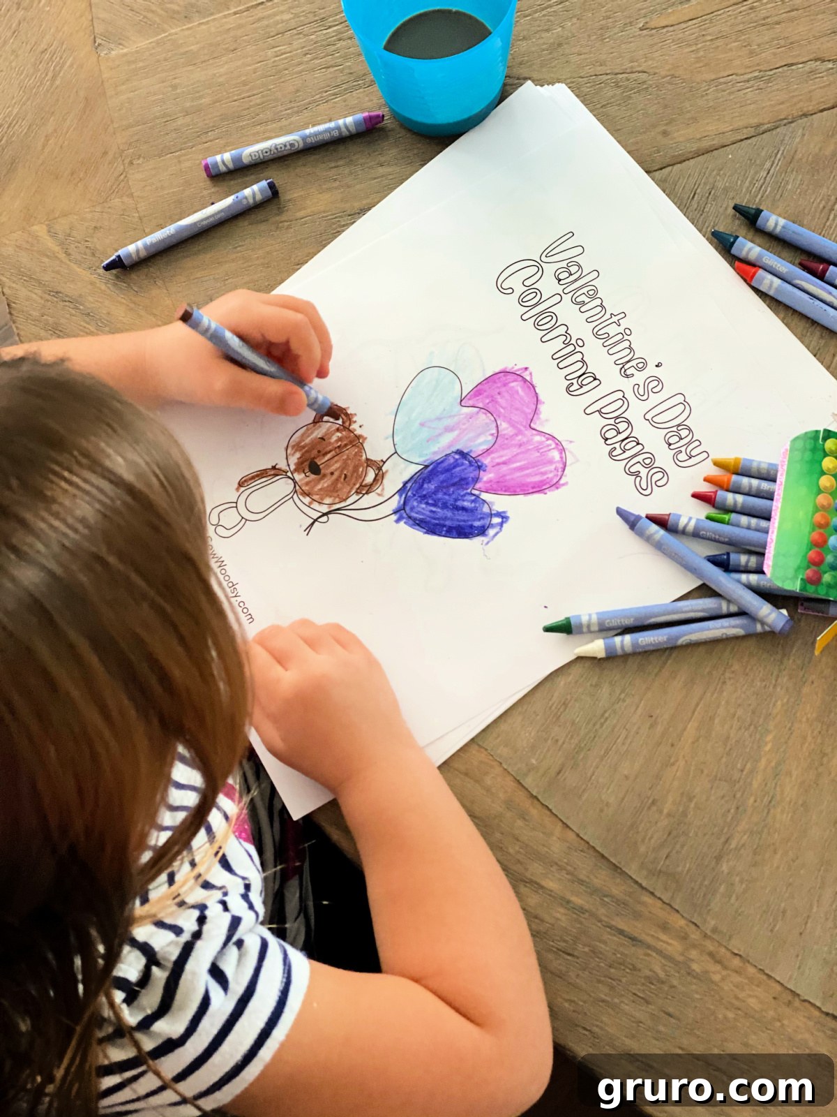 Sweetheart Valentine's Coloring Fun 2 A little girl intently coloring a cute bear holding balloons, with crayons scattered on the table.