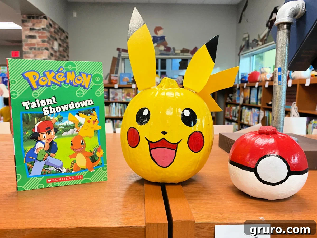 Yellow pikachu pumpkin with a red and white poke ball pumpkin and a Pokemon book next to it.