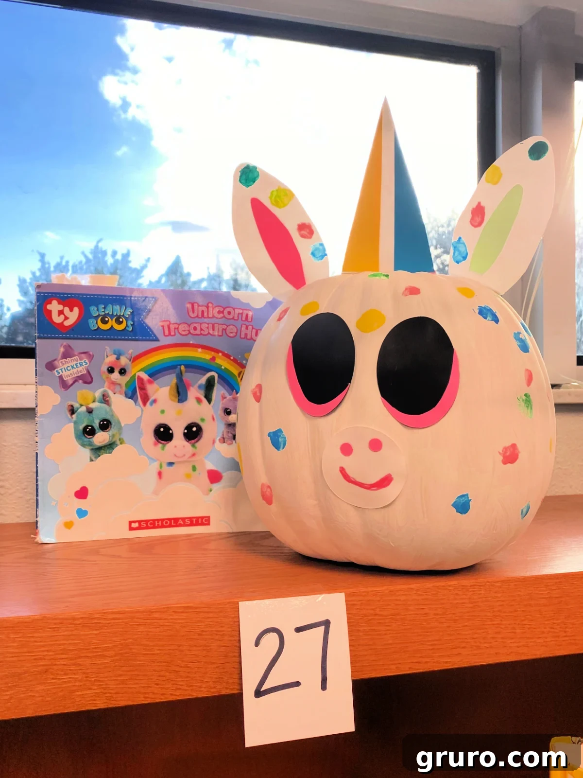 White unicorn pumpkin with book next to it.