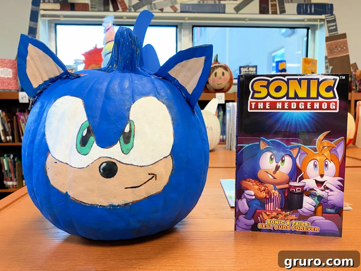 Blue sonic pumpkin on a wooden shelf next to a Sonic the Hedgehog book.