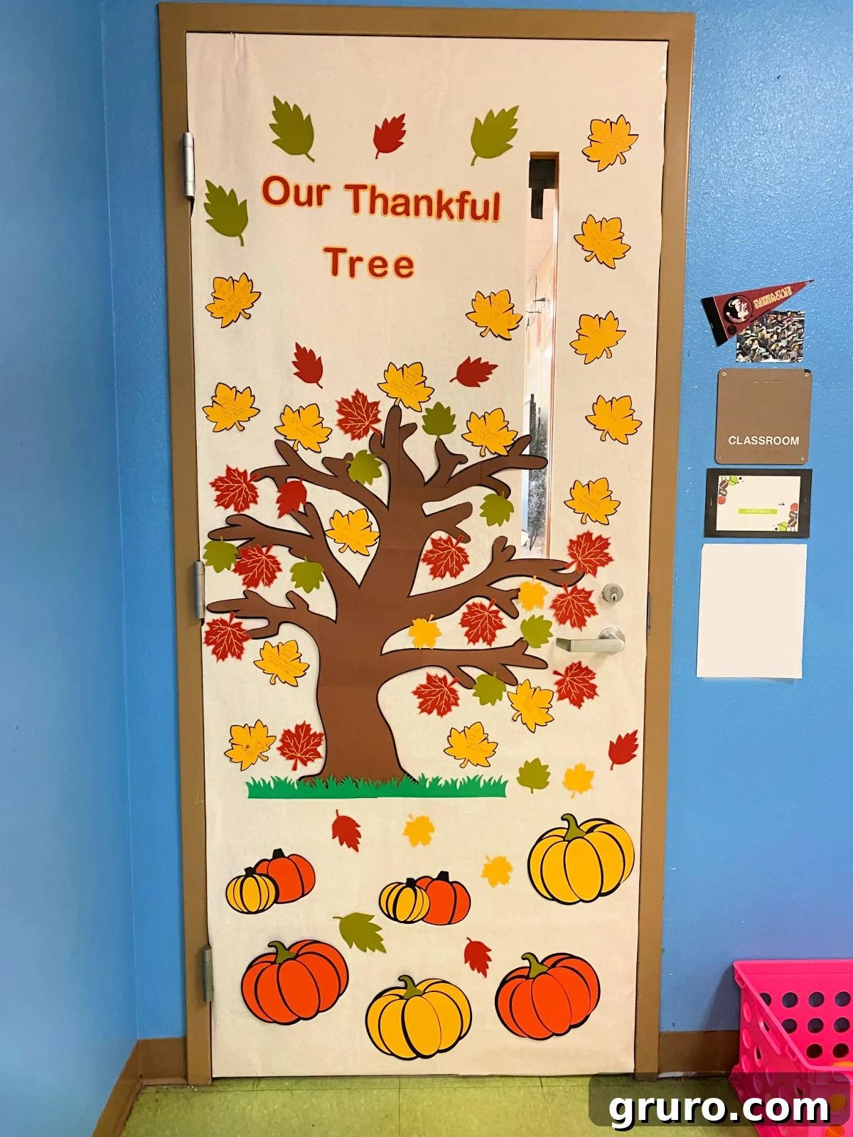 White classroom door with tree with fall leaves and pumpkins.