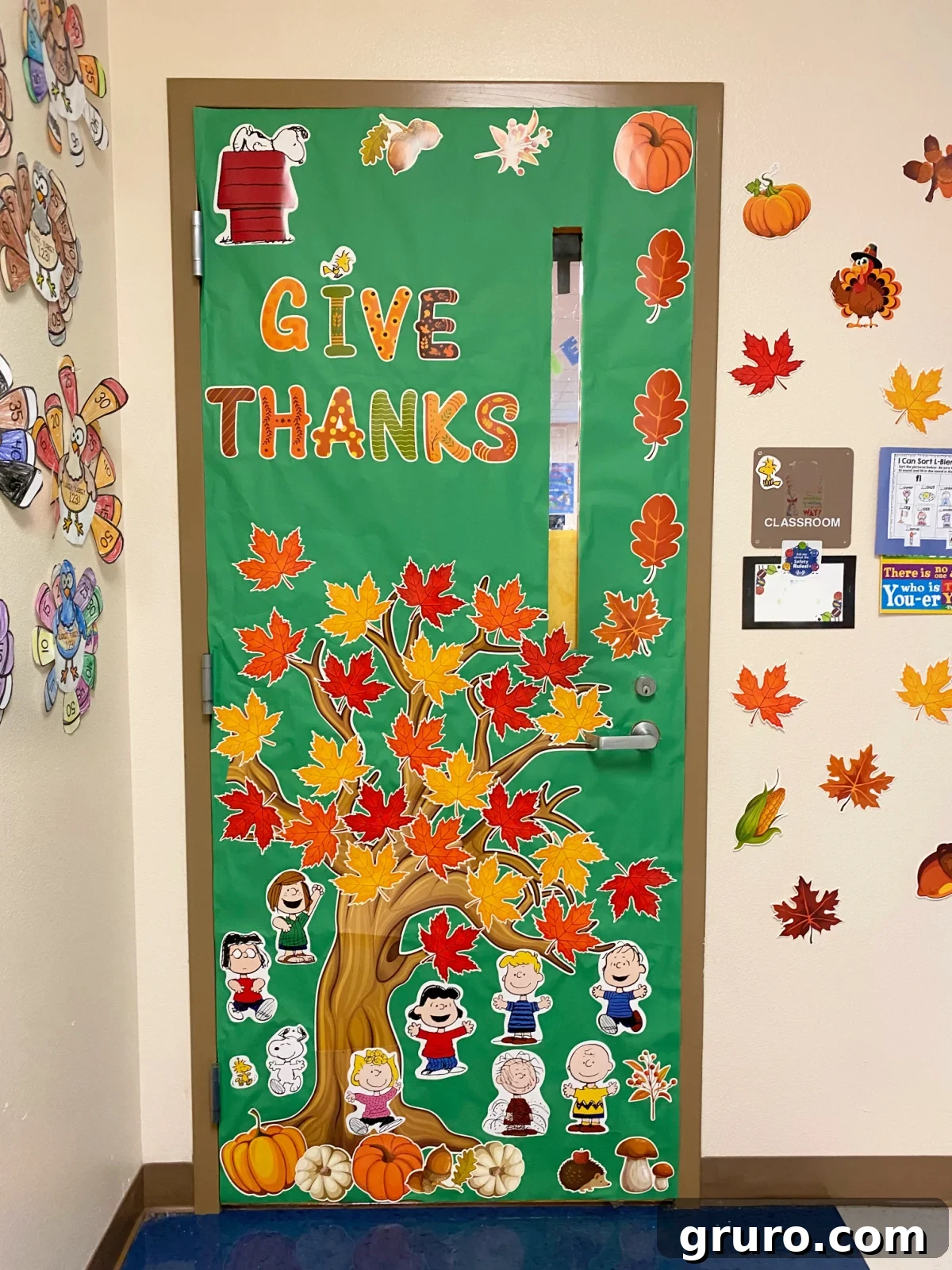 Green decorated door with a tree, fall leaves, and charlie brown characters.
