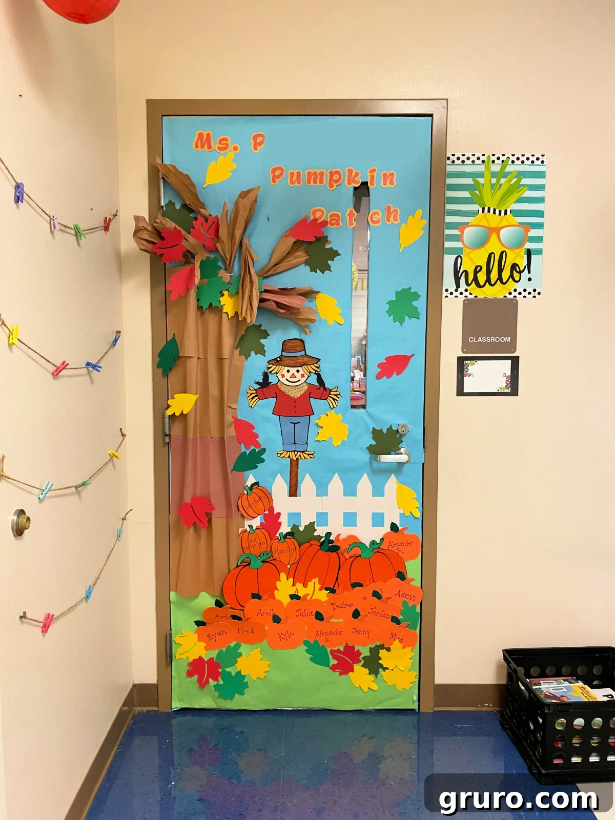 Tree with pumpkin patch, leaves, and a scarecrow decorated classroom door.