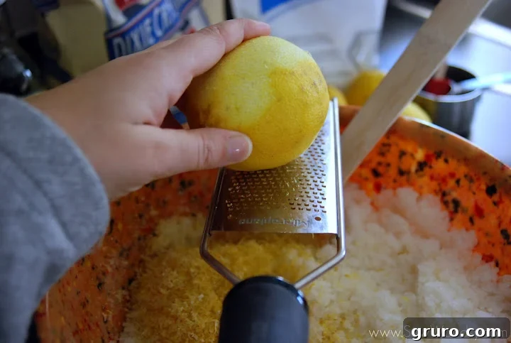 Lemon zest being grated directly into the sugar scrub mixture.