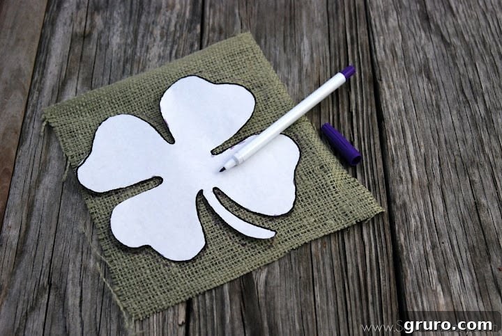 Tracing the four leaf clover stencil onto green burlap