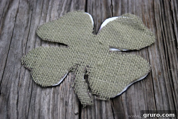 Cutting the green burlap four leaf clover with scissors