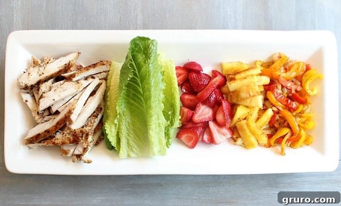 Close-up of a finished lettuce chicken wrap, showcasing grilled chicken, fresh fruit, and vegetables.