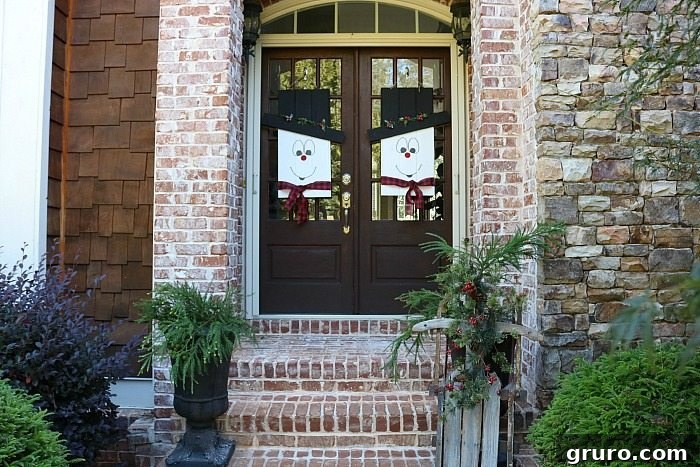 Close-up of a whimsical snowman door hanger, highlighting painted details and festive ribbon. Perfect winter door decor.