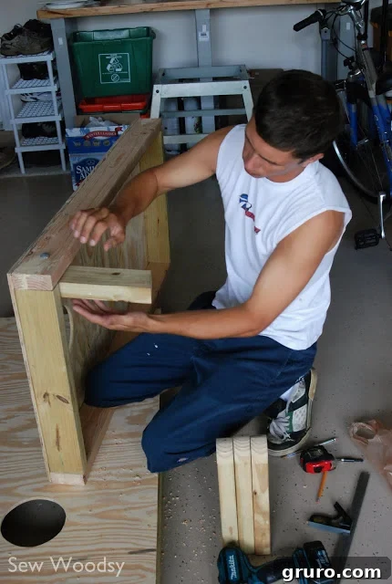 A person working on attaching the legs to a cornhole board