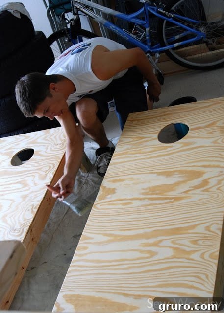 Cornhole board after applying wood filler and before sanding, showing smoothed surfaces